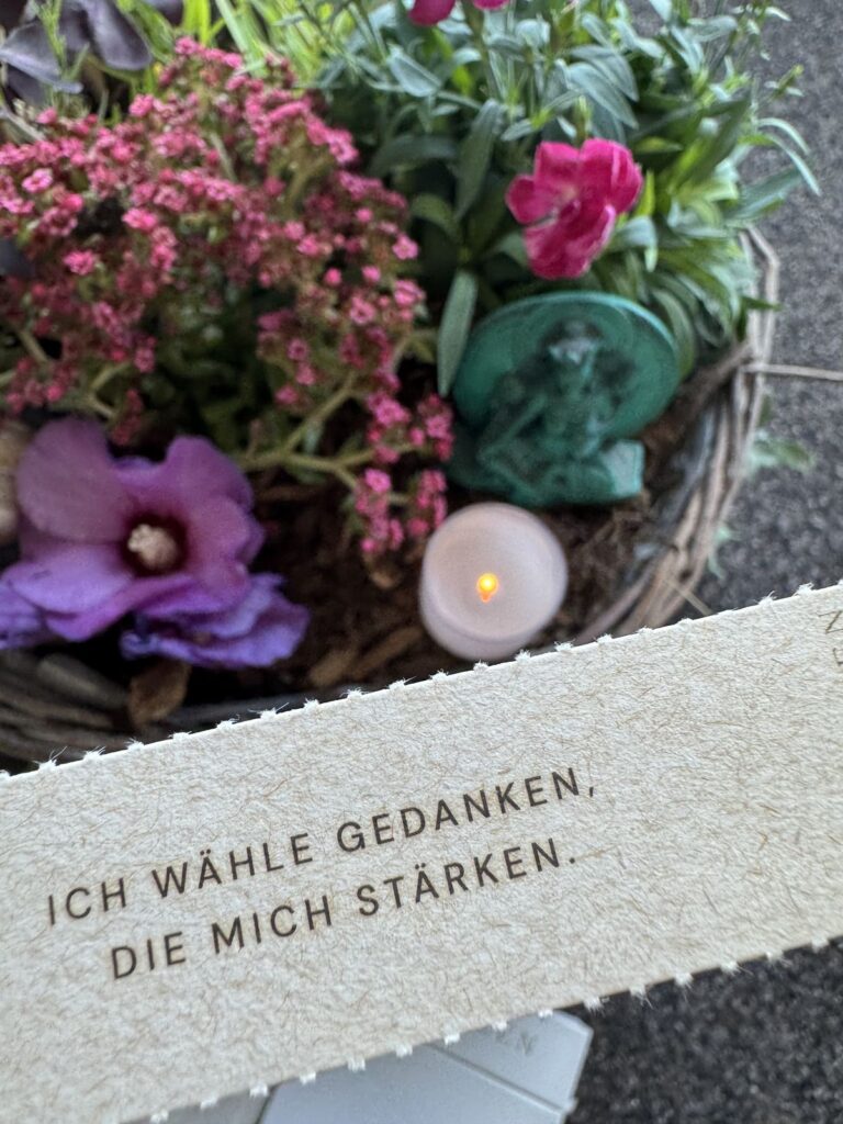 Karte mit dem Satz „Ich wähle Gedanken, die mich stärken“ vor Blumen und einer Kerze